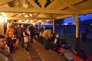Kerstritten Maasoever Spoorweg: verlicht station en vuurkorven langs spoor