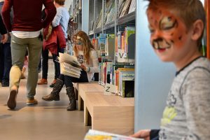 Kinderen lezen een boek in bibliotheek Het Kruispunt tijdens de officiële opening van Het Kruispunt